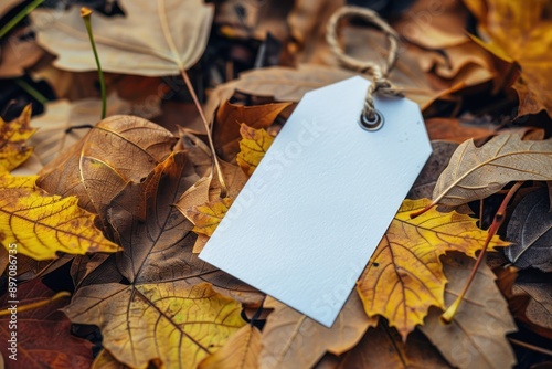 Empty white gift tag mockup. Paper label on autumn leaves coverered background. Minimal still life photo