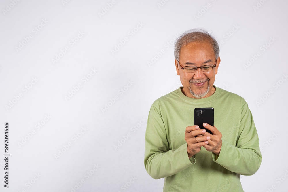 Portrait smiling Asian older man smiling holding a cell phone studio shot isolated on white background. elderly typing message on mobile phone in hand. Concept of connection and communication Portrait smiling Asian older man smiling holding a cell phone studio shot isolated on white background. elderly typing message on mobile phone in hand. Concept of connection and communication