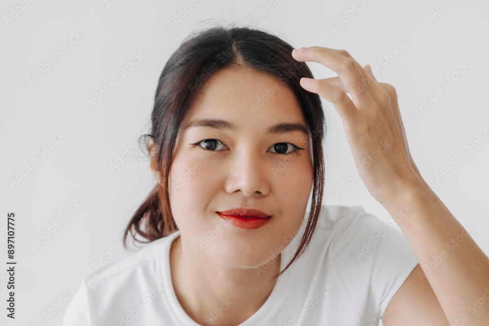 Close up of asian Thai woman hand touching hair, confidence smiling and looking at camera while standing isolated over white background wall. Close up of asian Thai woman hand touching hair, confidence smiling and looking at camera while standing isolated over white background wall.