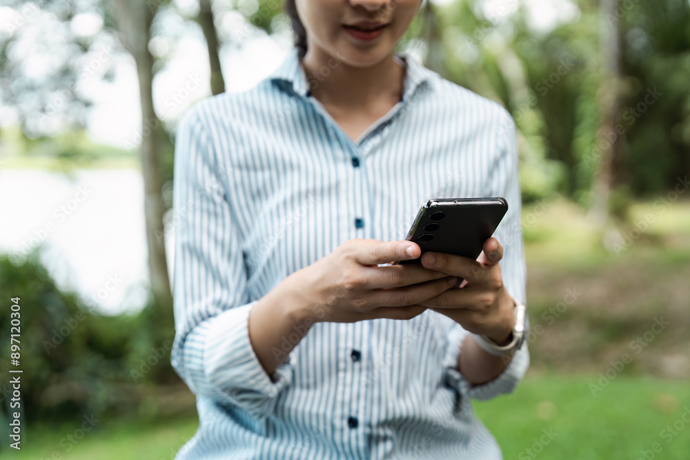 young student studying outdoors, holding a mobile and sitting at university park young student studying outdoors, holding a mobile and sitting at university park