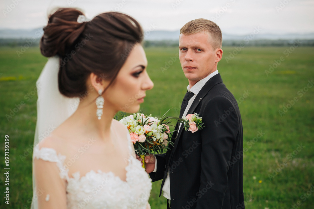 A bride and groom are standing in a field, with the bride holding a bouquet. The man is wearing a suit and tie, and the bride is wearing a white dress. Scene is romantic and happy A bride and groom are standing in a field, with the bride holding a bouquet. The man is wearing a suit and tie, and the bride is wearing a white dress. Scene is romantic and happy