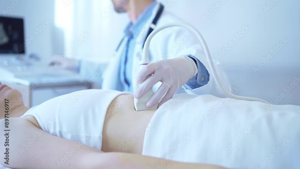 Doctor man wearing a white coat using an ultrasound machine on a female patient examining internal organs. Preventive therapy in medicine Doctor man wearing a white coat using an ultrasound machine on a female patient examining internal organs. Preventive therapy in medicine
