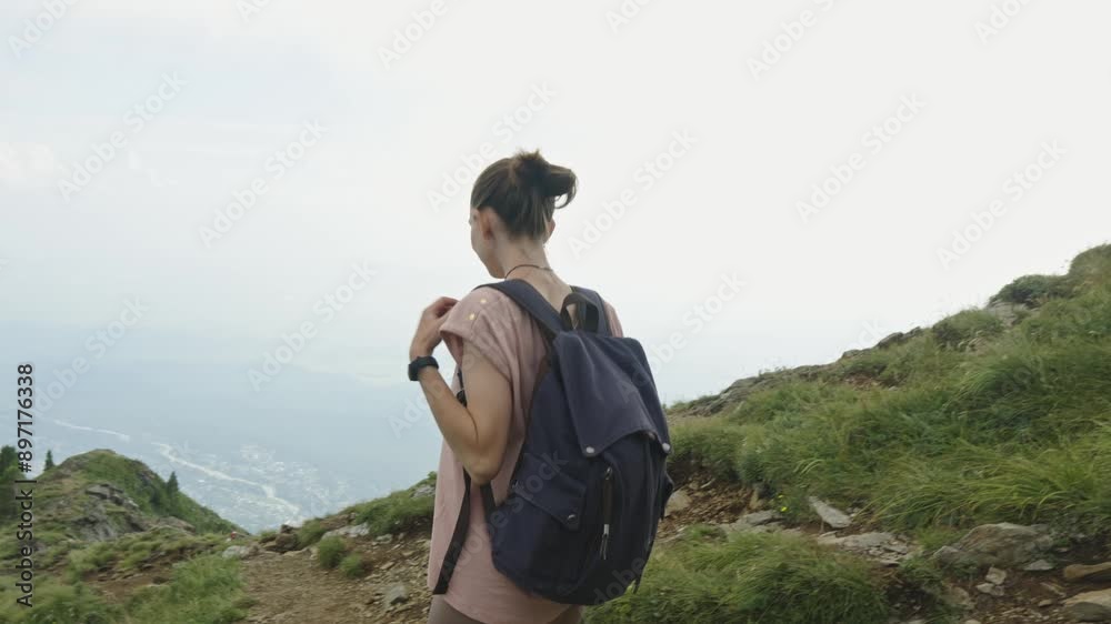 Woman tourist with a backpack while descending from the top against the background of a beautiful mountain landscape in summer. The concept of trekking trips and active life in nature. Slow motion Woman tourist with a backpack while descending from the top against the background of a beautiful mountain landscape in summer. The concept of trekking trips and active life in nature. Slow motion