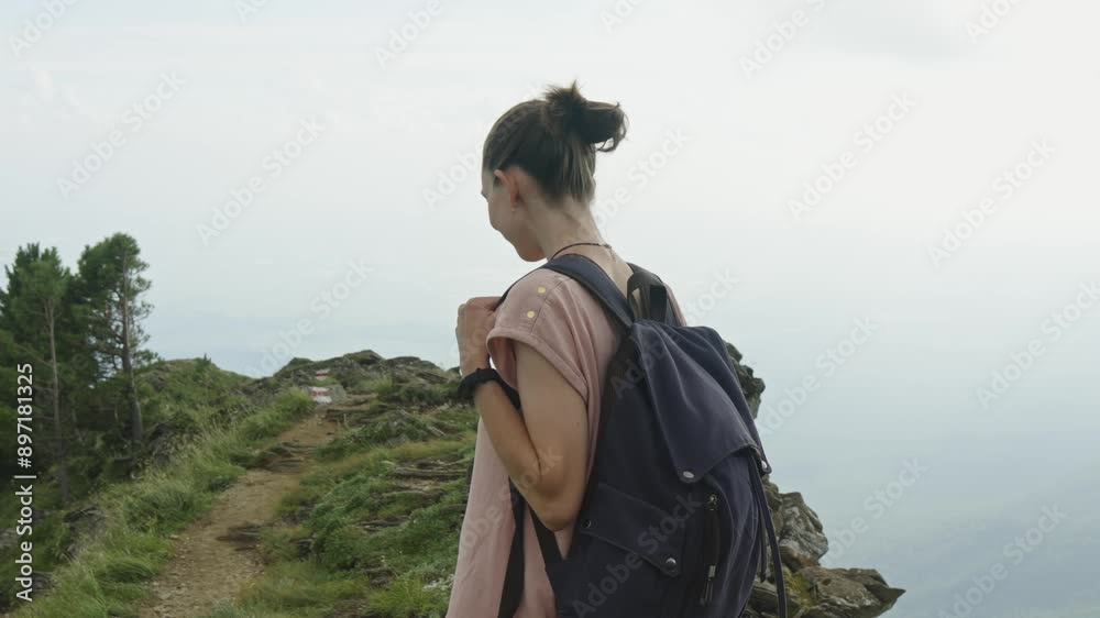Woman tourist with a backpack while descending from the top against the background of a beautiful mountain landscape in summer. The concept of trekking trips and active life in nature. Slow motion Woman tourist with a backpack while descending from the top against the background of a beautiful mountain landscape in summer. The concept of trekking trips and active life in nature. Slow motion