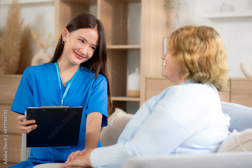 Caregiver sitting on sofa checkup and diagnostic with elderly woman patient about health in living room at home, caretaker sitting on couch explaining and examining senior, insurance and medical. Caregiver sitting on sofa checkup and diagnostic with elderly woman patient about health in living room at home, caretaker sitting on couch explaining and examining senior, insurance and medical.