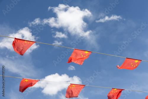 Canvas Print Wind blowing China flags fixed to two string lines against blue sky