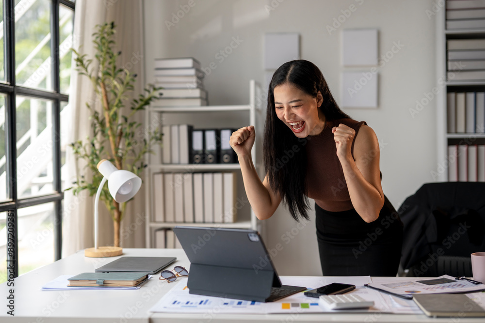 A woman is celebrating with her hands in the air in front of a computer A woman is celebrating with her hands in the air in front of a computer