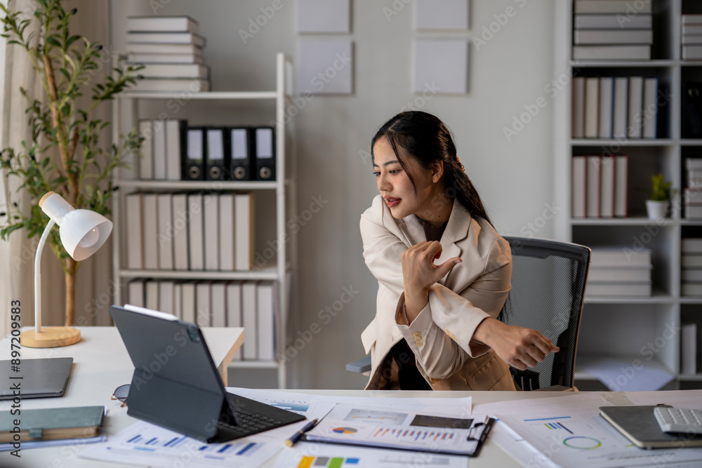 A woman in a business suit is sitting at a desk with a laptop A woman in a business suit is sitting at a desk with a laptop