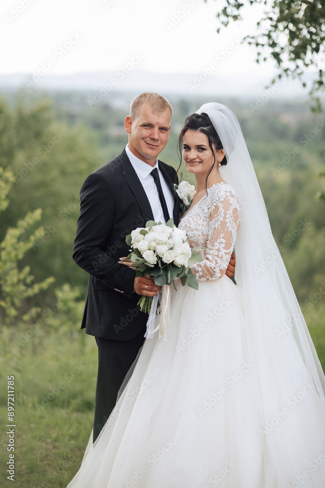 A bride and groom are posing for a picture in front of a tree. The bride is wearing a white dress and the groom is wearing a suit. The bride is holding a bouquet of flowers A bride and groom are posing for a picture in front of a tree. The bride is wearing a white dress and the groom is wearing a suit. The bride is holding a bouquet of flowers
