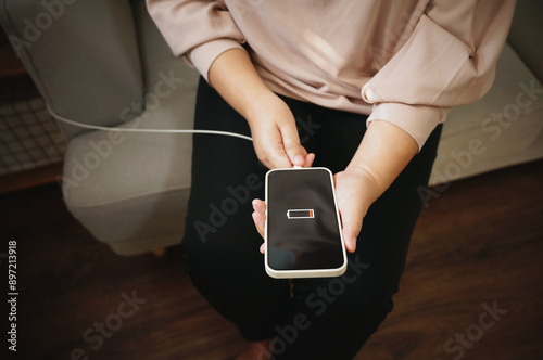Woman hands Charging mobile phone battery with low battery. plugging a charger in a smart phone with energy bank powerbank power charger Modern lifestyle energy technology concept