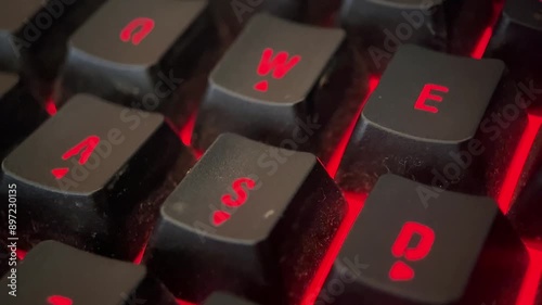 Close-up macro footage of a glowing RGB keyboard. The shot captures the intricate details of the backlit keys, showcasing a vivid array of colors and dynamic lighting effects
