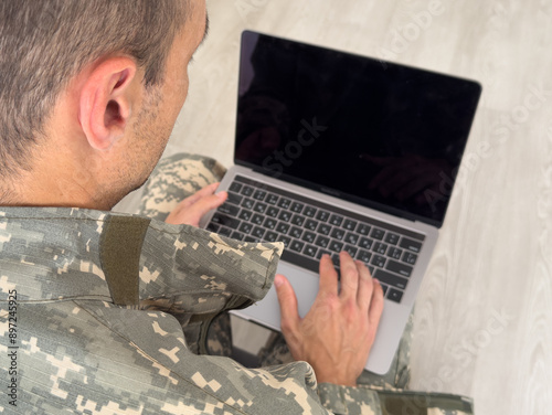 Foto Military service. Young soldier working at wooden table in office