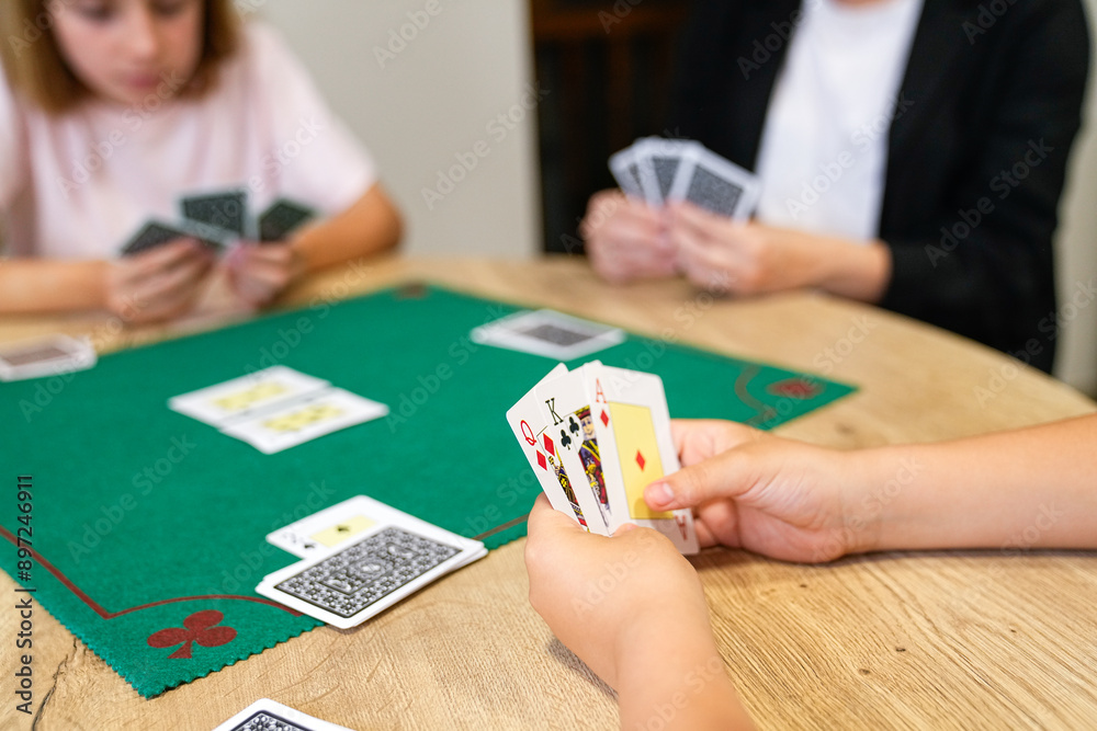 A group of people are playing a card game on a green table A group of people are playing a card game on a green table