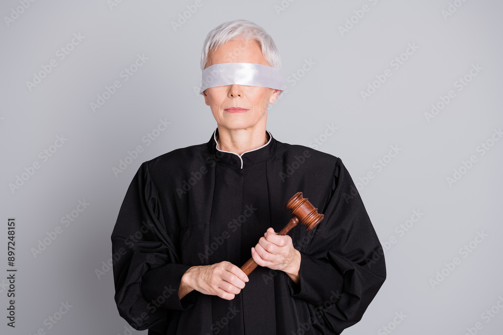 Photo of old serious woman judge with covered eyes hold wooden gavel isolated grey color background Photo of old serious woman judge with covered eyes hold wooden gavel isolated grey color background