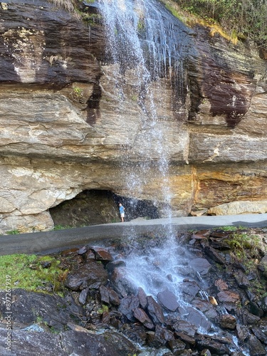 Woman standing behind Bridal Veil Falls near Highlands, North Carolina in the Nantahala National Forest photo