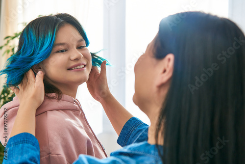 Valokuva An Asian mother with blue hair gently combing her teenage daughters hair in a casual home setting