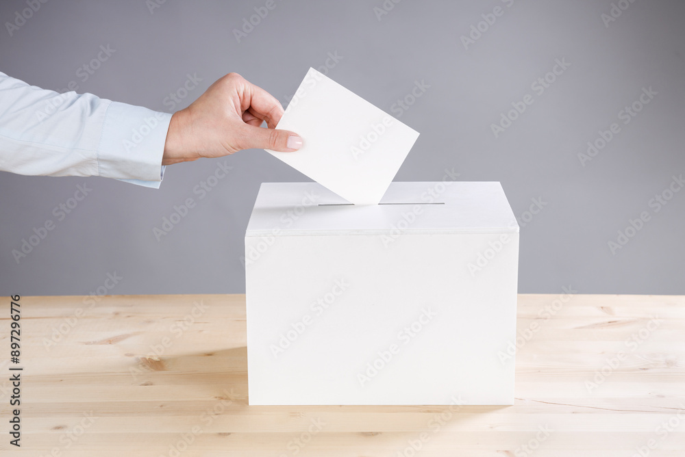 Woman's hand casting a vote and a ballot box Woman's hand casting a vote and a ballot box