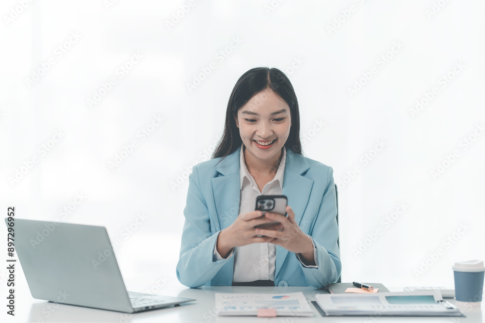 Asian businesswoman using laptop and talking on mobile phone Contact financial businesses online, talk to customers on the phone with a confident demeanor and effective communication skills. Asian businesswoman using laptop and talking on mobile phone Contact financial businesses online, talk to customers on the phone with a confident demeanor and effective communication skills.