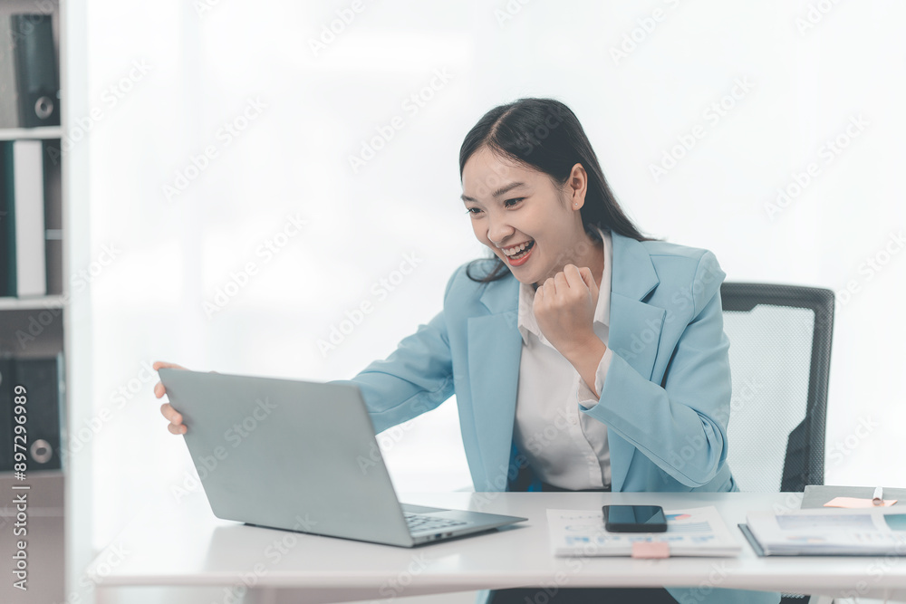 Excited Asian business woman with success in business puts her hands up in front of the computer while sitting at work. Excited Asian business woman with success in business puts her hands up in front of the computer while sitting at work.