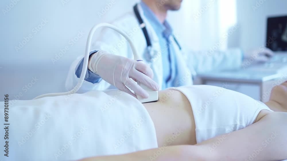 Doctor man wearing a white coat using an ultrasound machine on a female patient examining internal organs. Preventive therapy in medicine Doctor man wearing a white coat using an ultrasound machine on a female patient examining internal organs. Preventive therapy in medicine