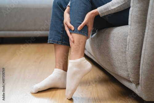 Woman get cramp on the leg sitting on sofa photo