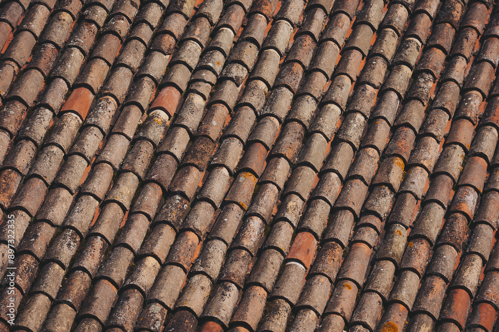 weathered tiles of old roof. Closeup of weathered rusty red tiles on roof of medieval building for textured background. weathered tiles of old roof. Closeup of weathered rusty red tiles on roof of medieval building for textured background.