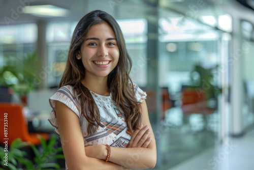 Portrait of smiling young multiethnic woman looking at camera with crossed arms. Successful latin business woman standing in modern office with copy space. Young university hispanic girl with smile. Free Download Portrait of smiling young multiethnic woman looking at camera with crossed arms. Successful latin business woman standing in modern office with copy space. Young university hispanic girl with smile. - GFXLoad