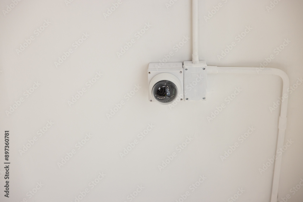 A white camera is mounted on a white wall