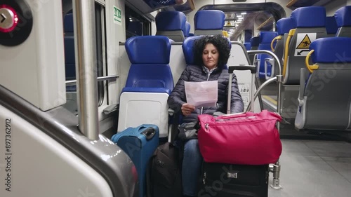 Hispanic woman traveling by train at train sitting and reading ticket safety measures from Fiumicino to Rome, Italy photo