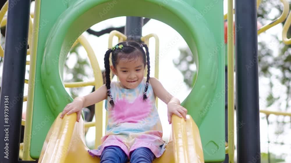 Happy Cute Asian Toddler Child Girl Playing on Modern Playground Slide, baby rides down slide. entertaining and relaxing the child on weekends. active outdoor recreation in the park. Happy Cute Asian Toddler Child Girl Playing on Modern Playground Slide, baby rides down slide. entertaining and relaxing the child on weekends. active outdoor recreation in the park.