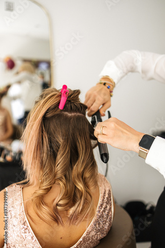 hairdresser curls a client's hair with a curling iron