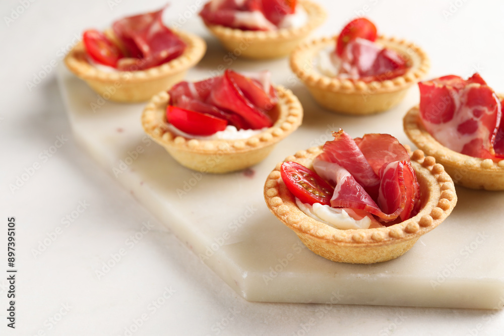 Delicious canapes with jamon, cream cheese and cherry tomatoes on light table, closeup Delicious canapes with jamon, cream cheese and cherry tomatoes on light table, closeup