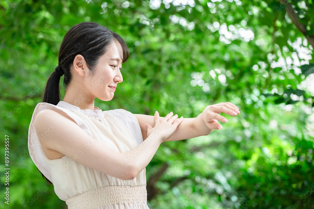 新緑の中で肌ケアをする女性 新緑の中で肌ケアをする女性