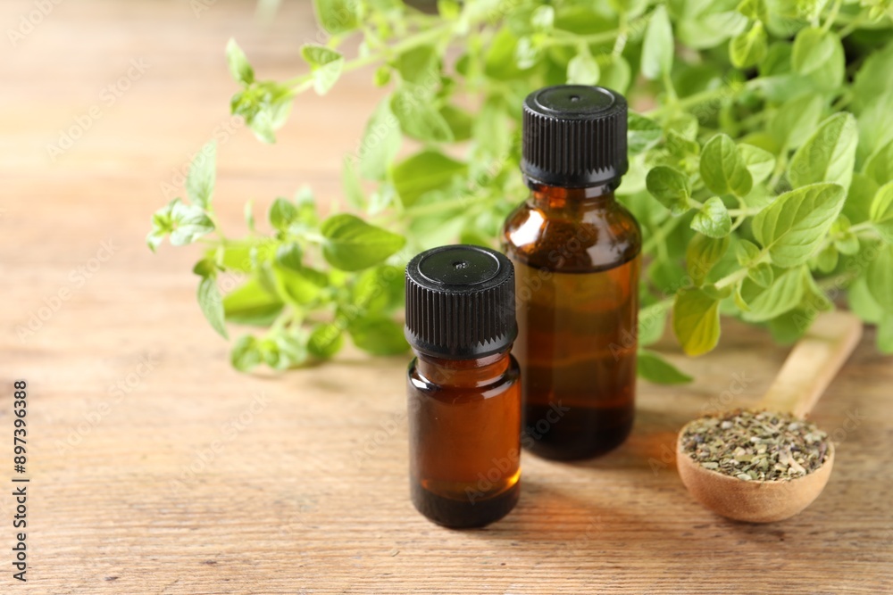Essential oil in bottles, spoon with dry herb and oregano twigs on wooden table, closeup. Space for text Essential oil in bottles, spoon with dry herb and oregano twigs on wooden table, closeup. Space for text