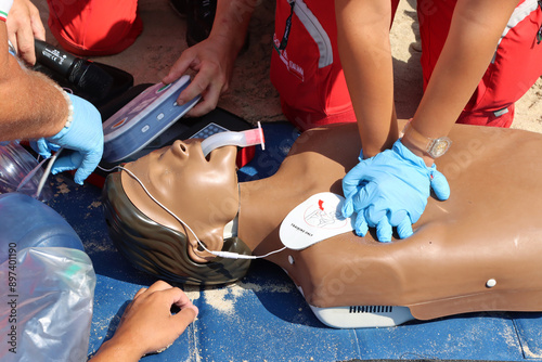 Fototapeta Naklejka Na Ścianę i Meble -  Exercise by Red Cross nurses and doctors on an Italian beach. Cardiac massage on a mannequin. Cardiocirculatory arrest, drowning at sea