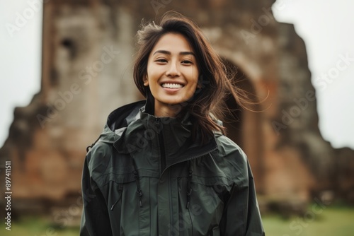 Portrait of a blissful asian woman in her 20s wearing a windproof softshell in backdrop of ancient ruins photo