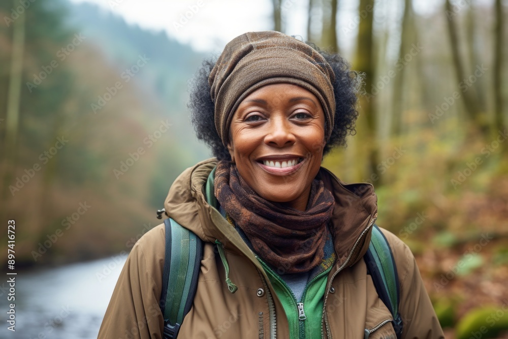 Portrait of a blissful afro-american woman in her 60s wearing a windproof softshell on tranquil forest stream Portrait of a blissful afro-american woman in her 60s wearing a windproof softshell on tranquil forest stream