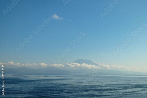 Wallpaper Mural A peaceful view of the calm ocean with a distant mountain under a clear blue sky, creating a serene and tranquil atmosphere. Torontodigital.ca