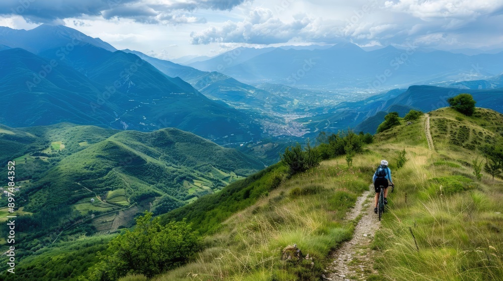 Solo mountain biker rides on a trail overlooking a valley. Solo mountain biker rides on a trail overlooking a valley.