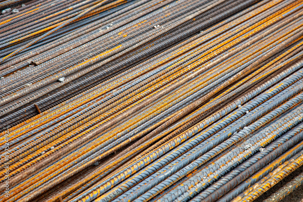 Close-up of steel rebar at a construction site. The textured bars are aligned and ready for use in reinforced concrete structures, showcasing the strength and precision of modern engineering. Close-up of steel rebar at a construction site. The textured bars are aligned and ready for use in reinforced concrete structures, showcasing the strength and precision of modern engineering.
