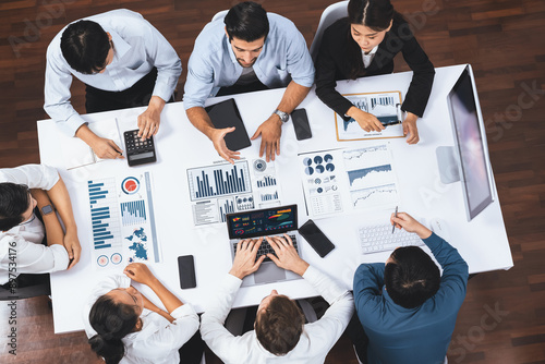 Top view analyst team utilizing BI Fintech to analyze financial data at table in meeting room. Analytic BI dashboard power on paper for business insight and strategic marketing planning. Prudent