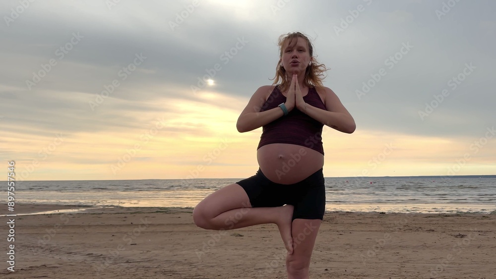 Young pregnant active woman doing exersice outdoors, stratching her body and meditate on the sea, beach at sunset in the evening Young pregnant active woman doing exersice outdoors, stratching her body and meditate on the sea, beach at sunset in the evening