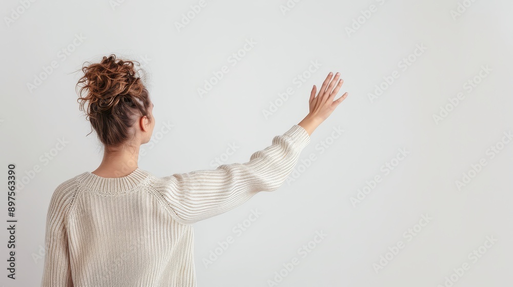 Woman in a beige sweater raising hand against white background