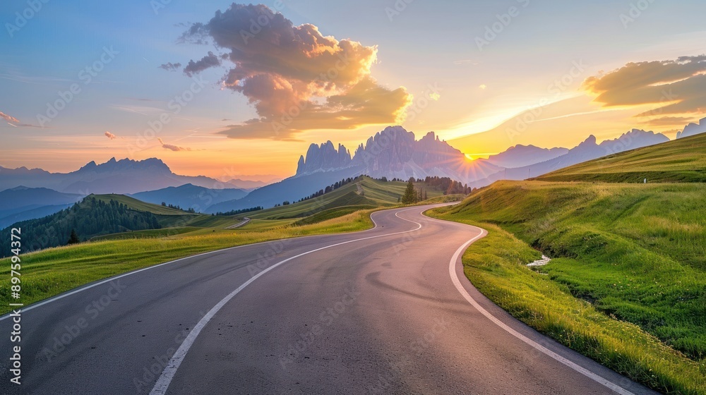 Fototapeta premium Winding Road Through Green Hills at Sunset With Mountain Peaks in the Background