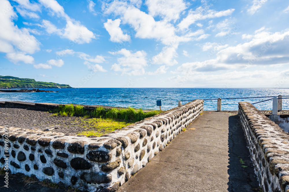 Obraz premium Coastal promenade along Almoxarife beach with azure ocean water, Faial island, Azores, Portugal