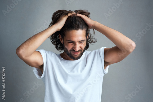 Stress, studio and man pulling hair with mental health, frustrated pain and thinking of mistake. Anxiety, anger and confused male person with depression, headache or brain fog on grey background