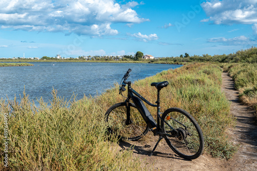 Photography un vélo électrique posé au bord d'un étang, de Camargue sous un ciel bleu