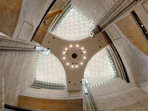 Interior view of a modern atrium with a geometric ceiling and concrete walls, emphasizing innovative architecture and contemporary design.