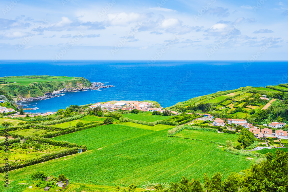 Fototapeta premium View of ocean, green farming fields and hills with flowers on north eastern coast of Sao Miguel island, Azores, Portugal