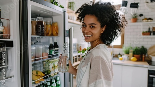 Attractive female checking the smart fridge inventory, with a sleek kitchen